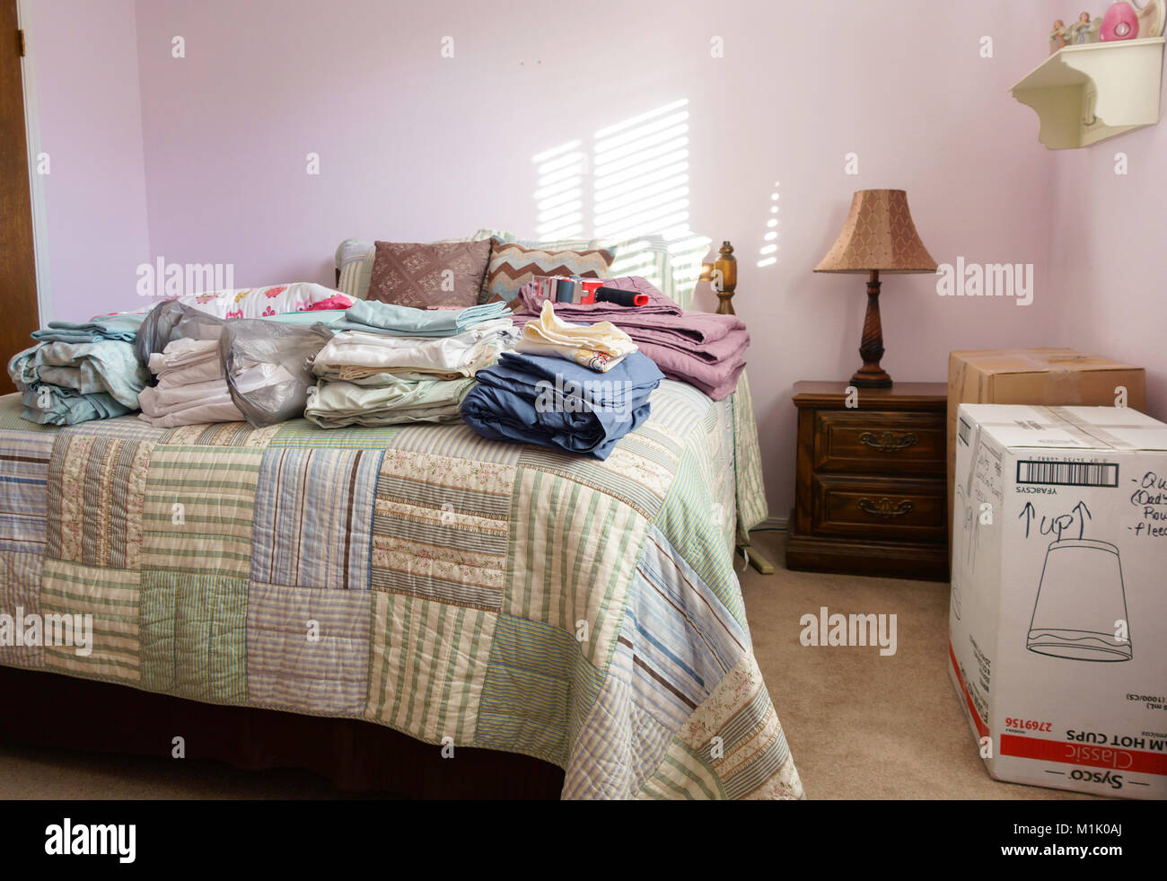 A bedroom with a stack of linens on the bed ready to be packed for a move. USA. Stock Photo
