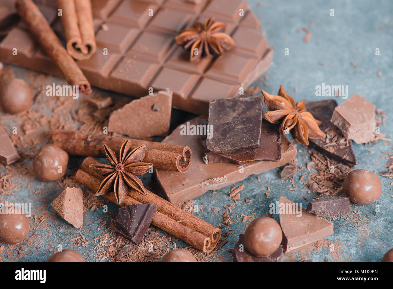 Dessert ingredients close-up. Chocolate pieces with spices and scattered cocoa on a stone background. Confectionery food photography. Stock Photo
