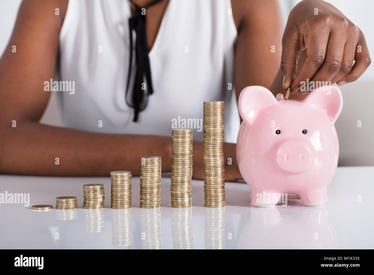 Human Hand Putting Coin In Piggybank Besides Stacked Coins Stock Photo ...