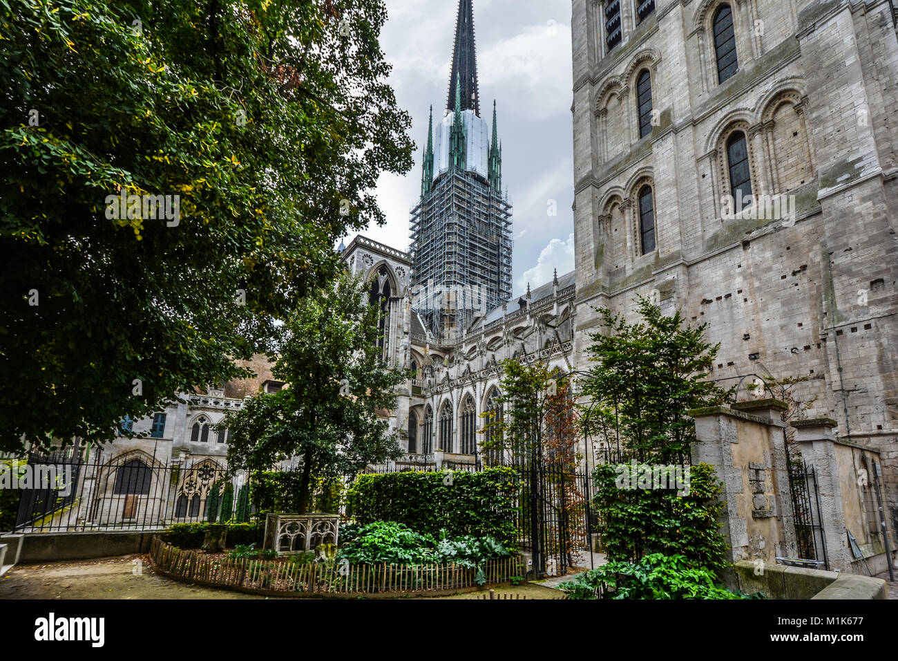 The garden and cloister of the medieval Notre Dame Cathedral of Rouen France in the Normandy region with scaffolding on the tower. Stock Photo