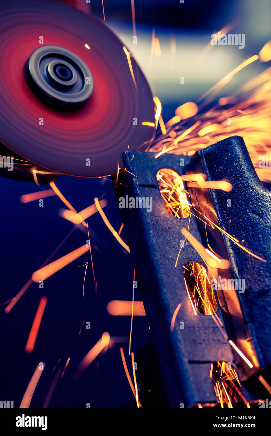 Metal bar being cut with electric grinder with spark flying, selective focus Stock Photo