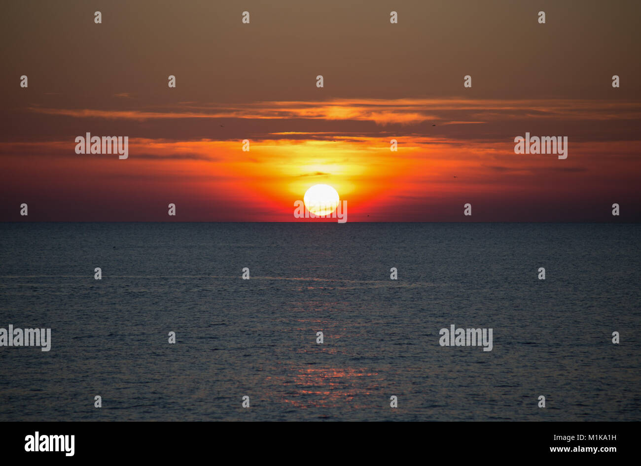 A beautiful sun setting on the horizon on the sea Stock Photo