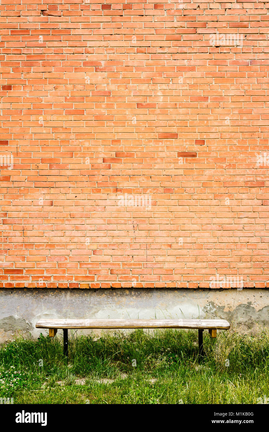 Old wooden bench by red brick wall with green grass Stock Photo - Alamy