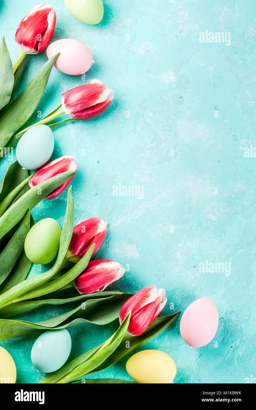 Multicolored Easter eggs with tulips flowers on a light blue background ...