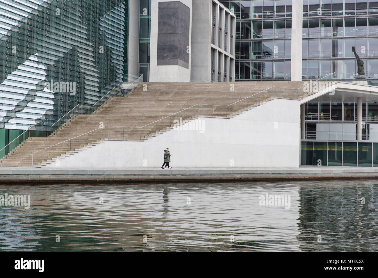 Couple walking along the river Spree surrounded by modern architecture of government district in German capital Berlin Stock Photo