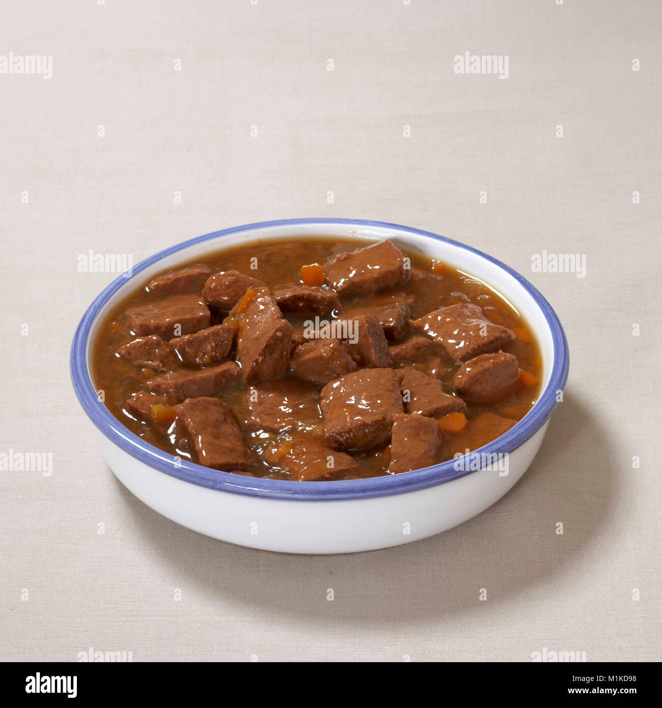 Domestic dog. Food bowl filled with moist feed seen against a white background Germany Stock Photo