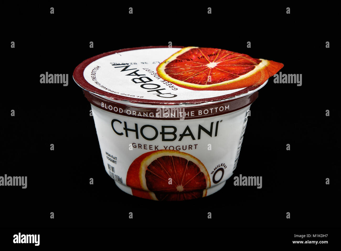 New York, December 4, 2017:  Tub of Chobani blood orange yogurt stands against black background. Stock Photo