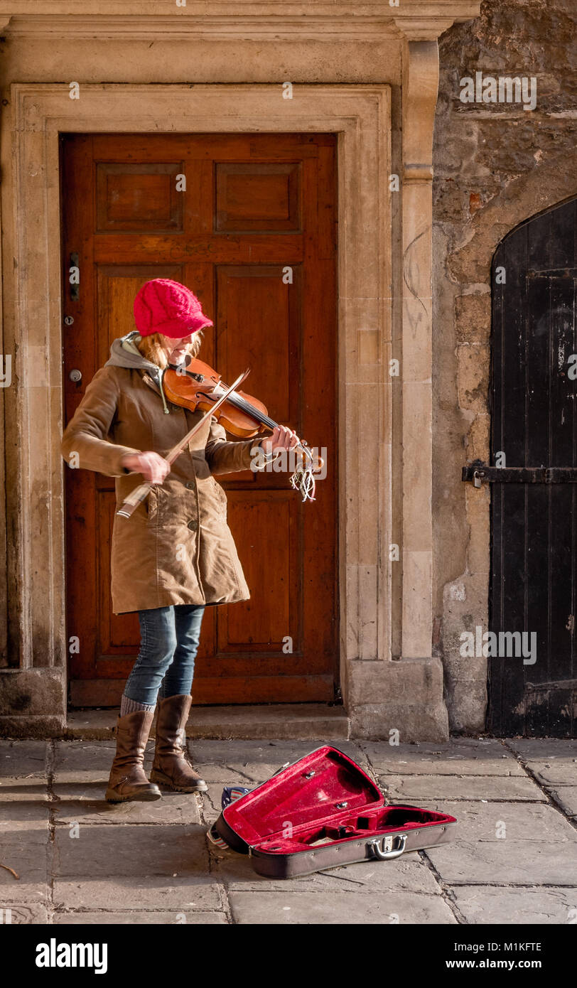 A woman violinist in a red hat busking in Wells city centre Somerset UK Stock Photo