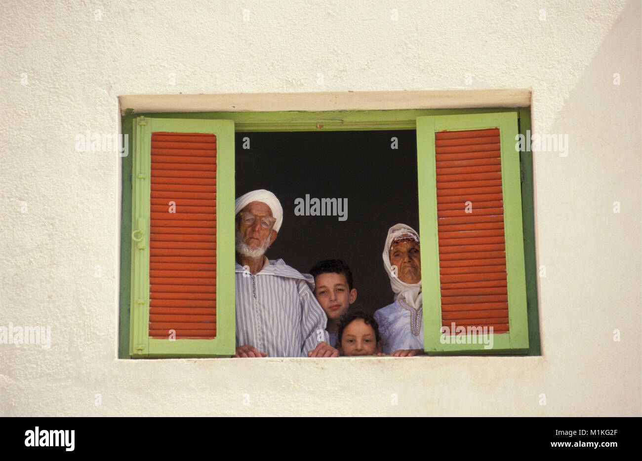 Morocco. Kassita. Rif Mountains. Family of Berber tribe (grandfather,  grandmother and 2 children) looking out window. Stock Photo