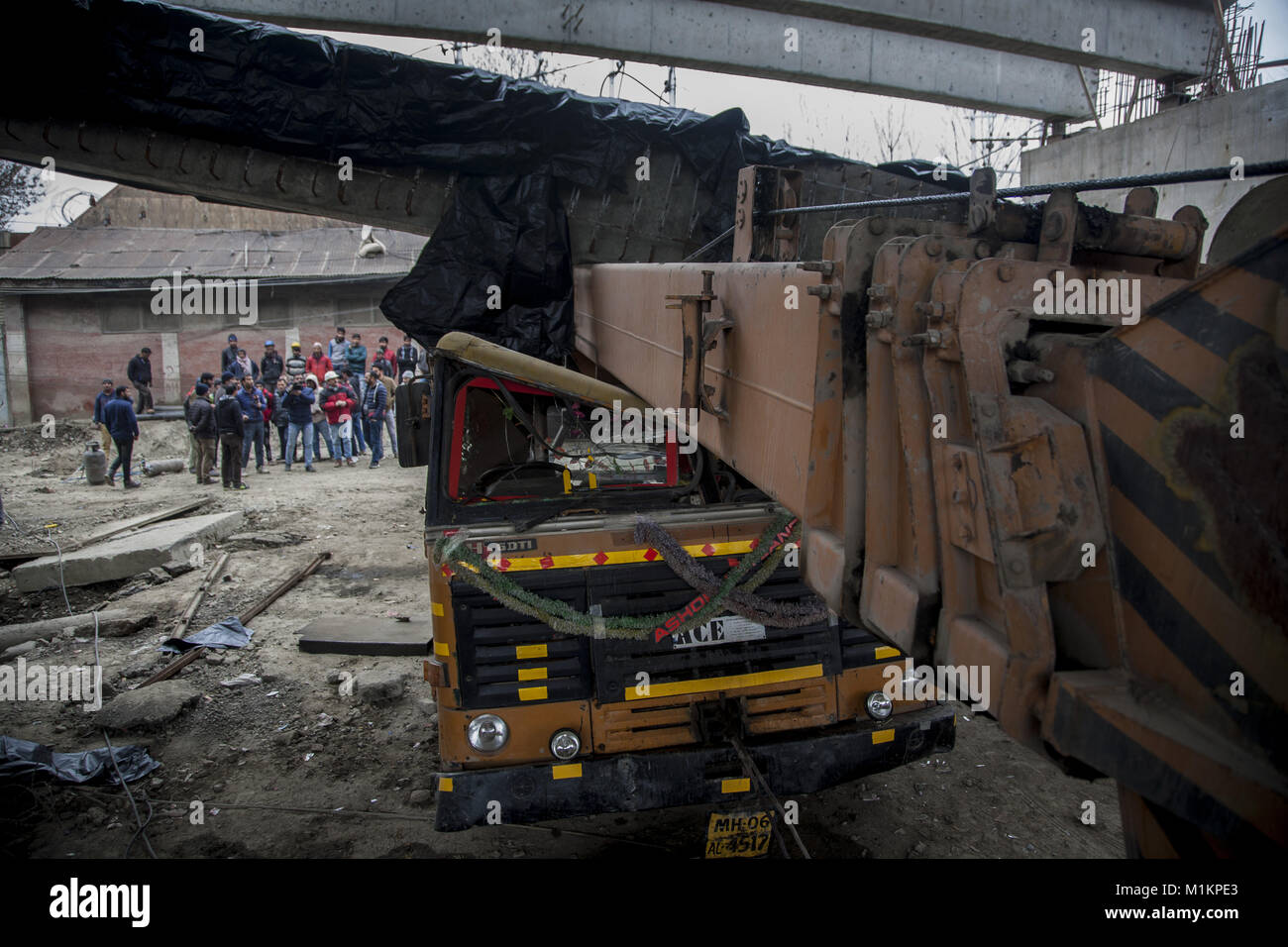 January 31, 2018 - Srinagar, Jammu and Kashmir, India - People look at a girder lying on a vehicle damaged after it fell from an under construction flyover following a powerful earthquake struck northern Afghanistan with tremors felt as widely as Pakistan and northern India, on January 31, 2018 in Srinagar, the summer capital of Indian administered Kashmir, India. The magnitude 6.1 quake was centered in the mountainous Hindu Kush region, the US Geological Survey reported. A young girl was killed and five others wounded in the village of Lasbela in Pakistan's Baluchistan province when the ro Stock Photo