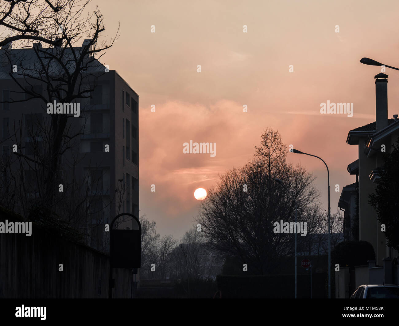 the sun sets behind the buildings on a cold winter afternoon, coloring the sky Stock Photo