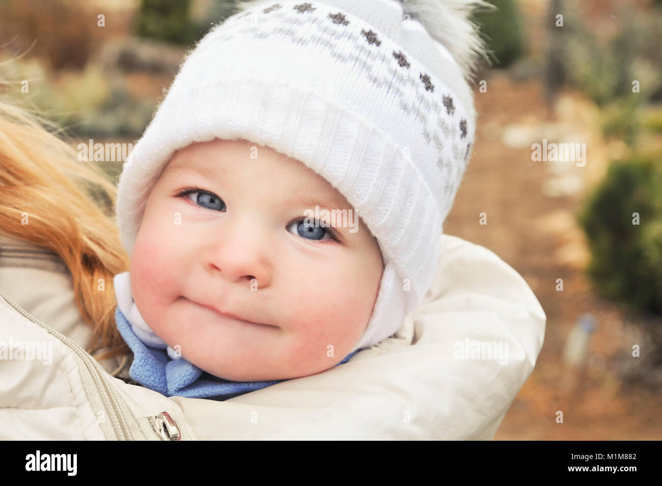 A child in a sling at the mother's under a jacket, a portrait of a baby