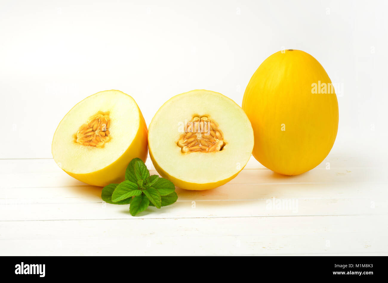 whole and halved yellow melons Stock Photo
