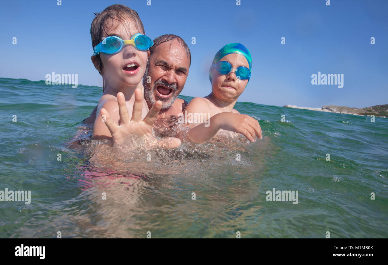 Grandfather and couple kids are playing in the sea or ocean waters. Stock Photo