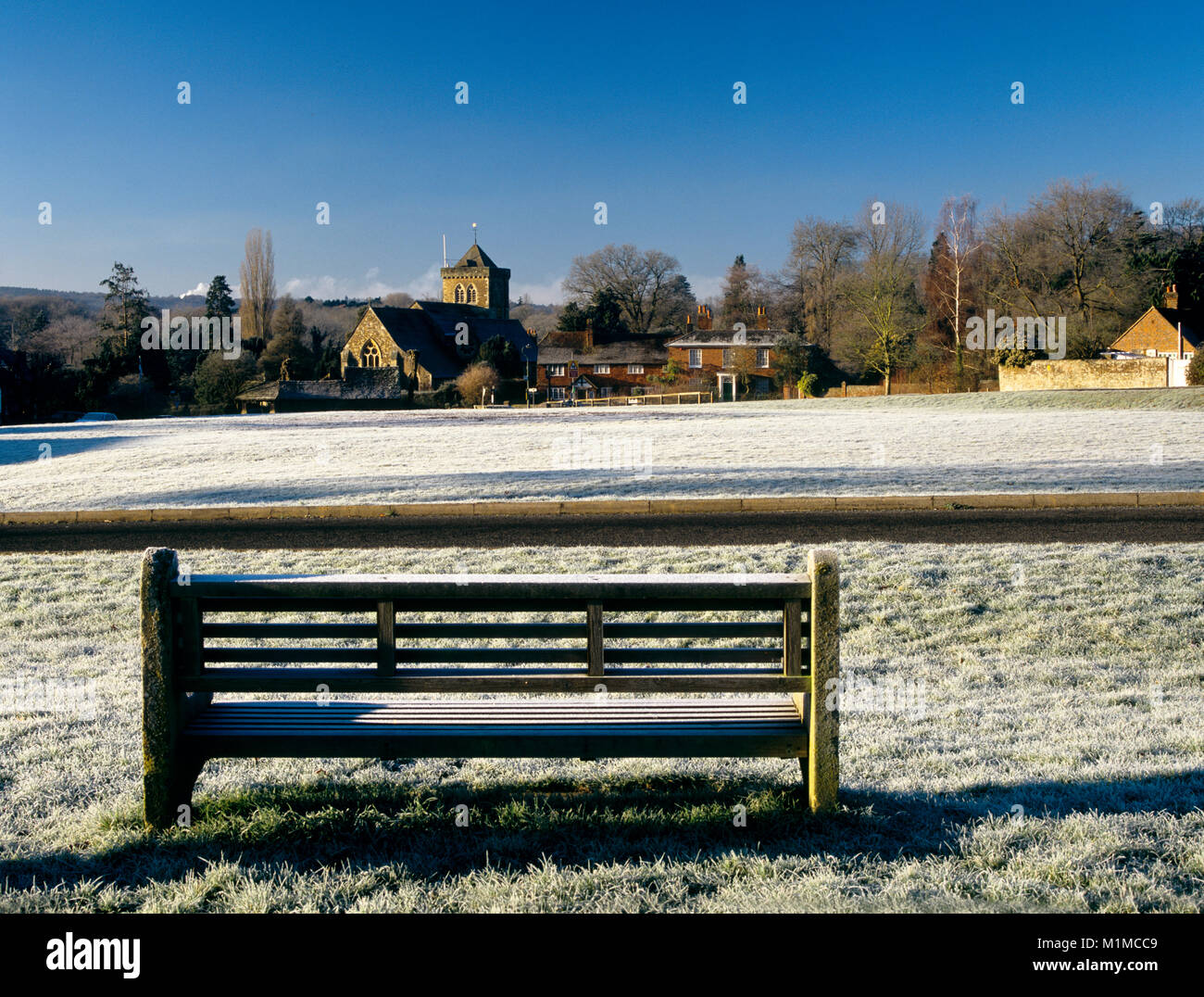 Looking across the village green towards the village church Chiddingfold Surrey England UK on a cold frosty winters day with cloudless blue sky Stock Photo