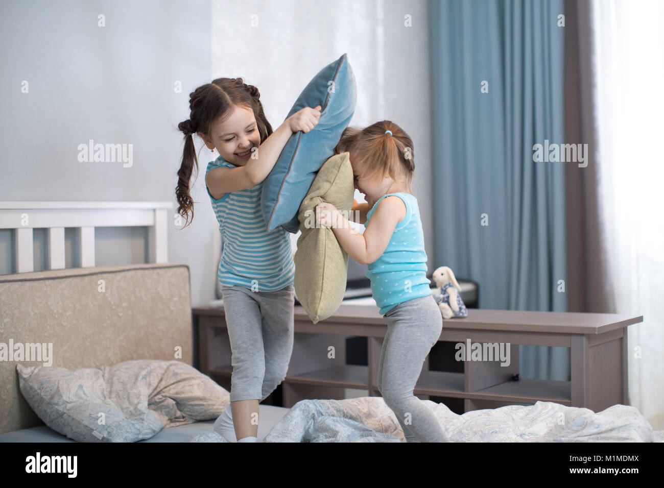 Two kids sisters girls playing with pillows at home Stock Photo