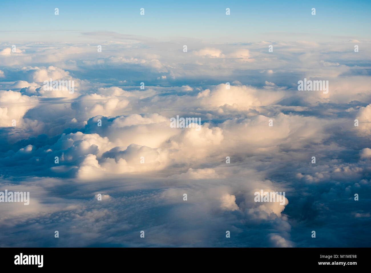 Aerial view over cumulus clouds from an airplane window during the ...