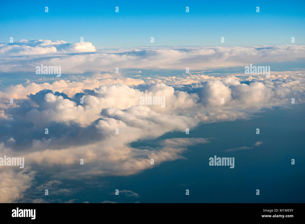 Aerial view over cumulus clouds from an airplane window during the ...