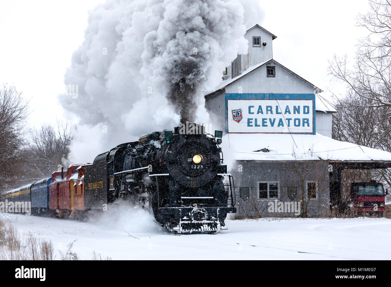 The Pere Marquette 1225 “North Pole Express” passes Carland Elevator, spewing steam on a snowy day Stock Photo