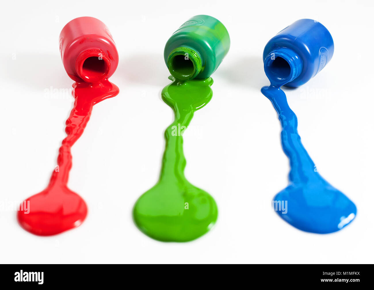 Red, green and blue paint pots with paint spill Stock Photo