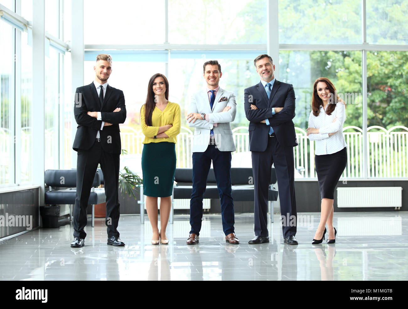 Happy business team with arms crossed at the office Stock Photo - Alamy