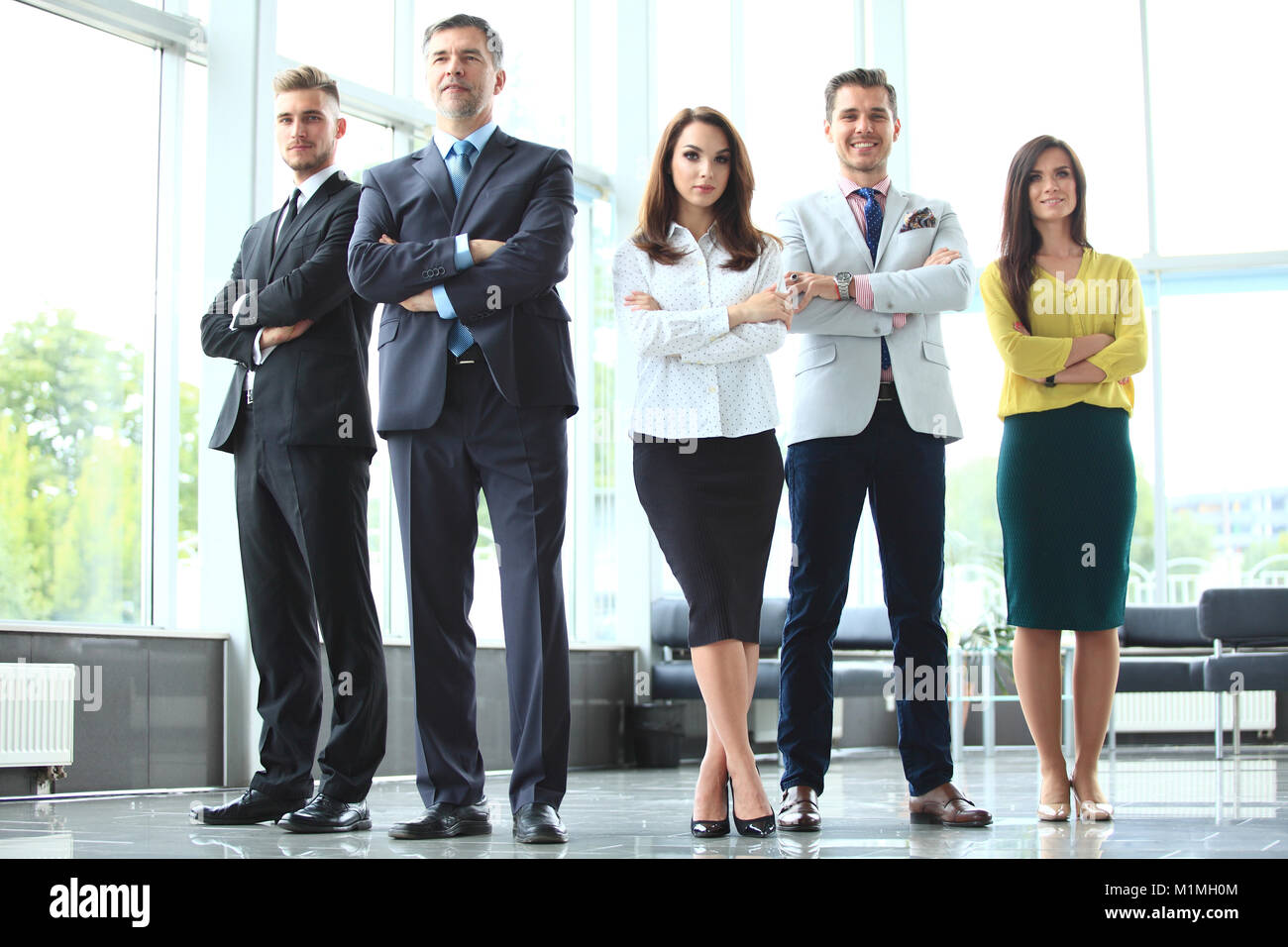 Happy business team with arms crossed at the office Stock Photo - Alamy