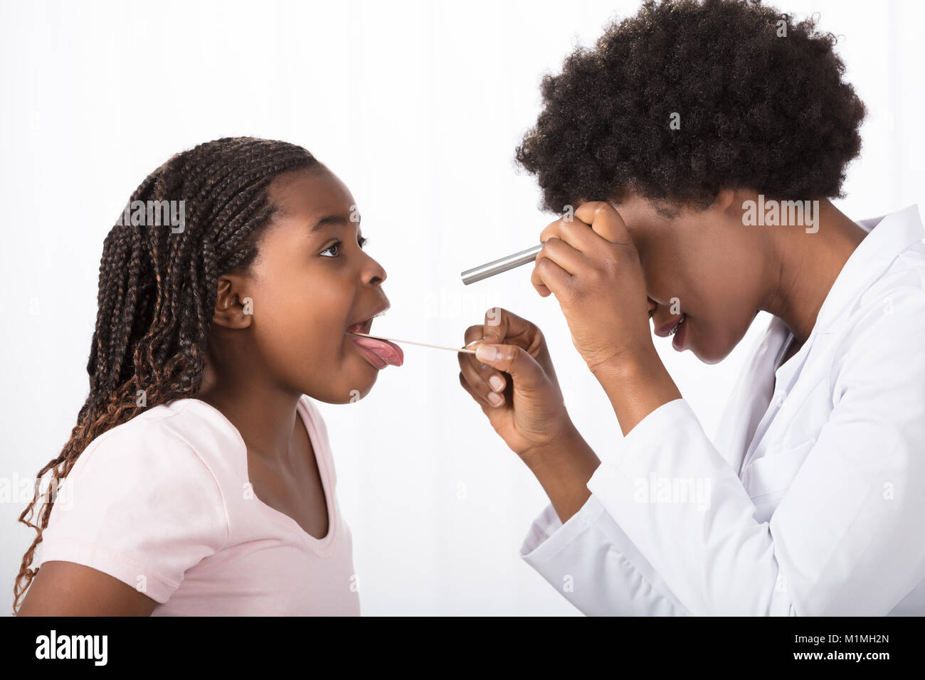 Close-up Of A Young Female Doctor Checking His Patient's Throat In Clinic Stock Photo