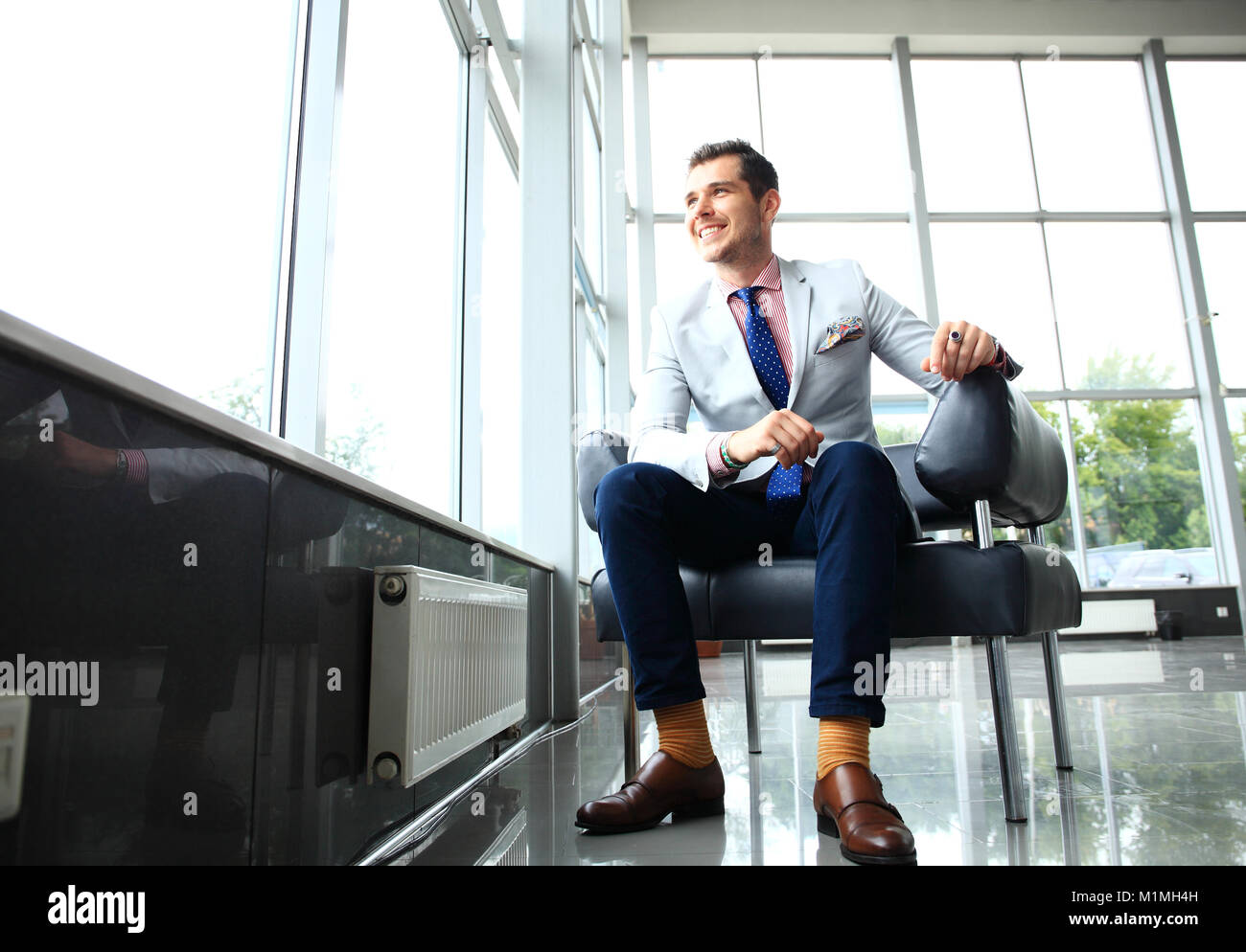 Low angle shot of a handsome young businessman in a stylish modern office space with large windows. Stock Photo