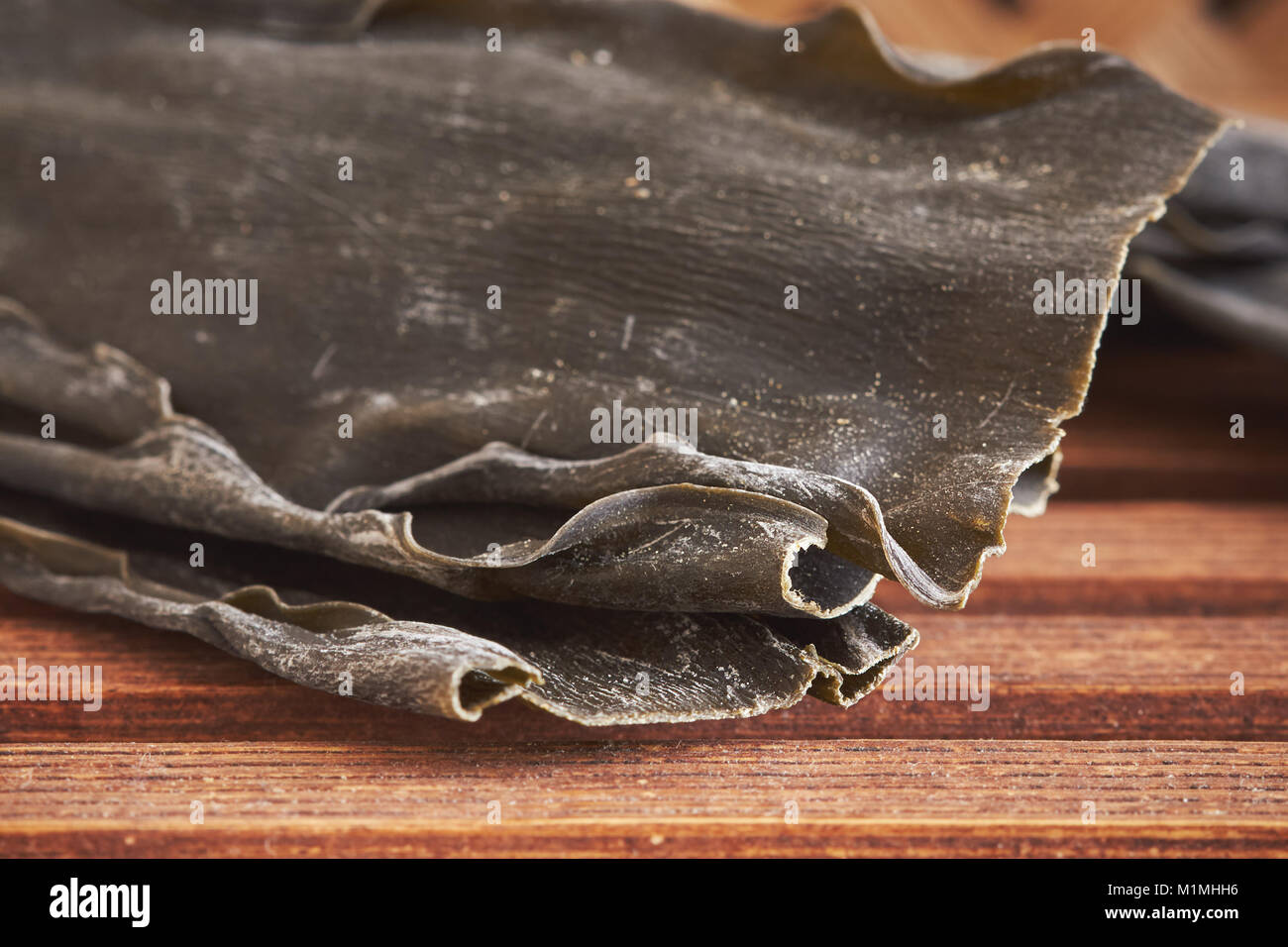 Closeup of dried kombu seaweed (Laminariaceae longissima) on wooden background Stock Photo
