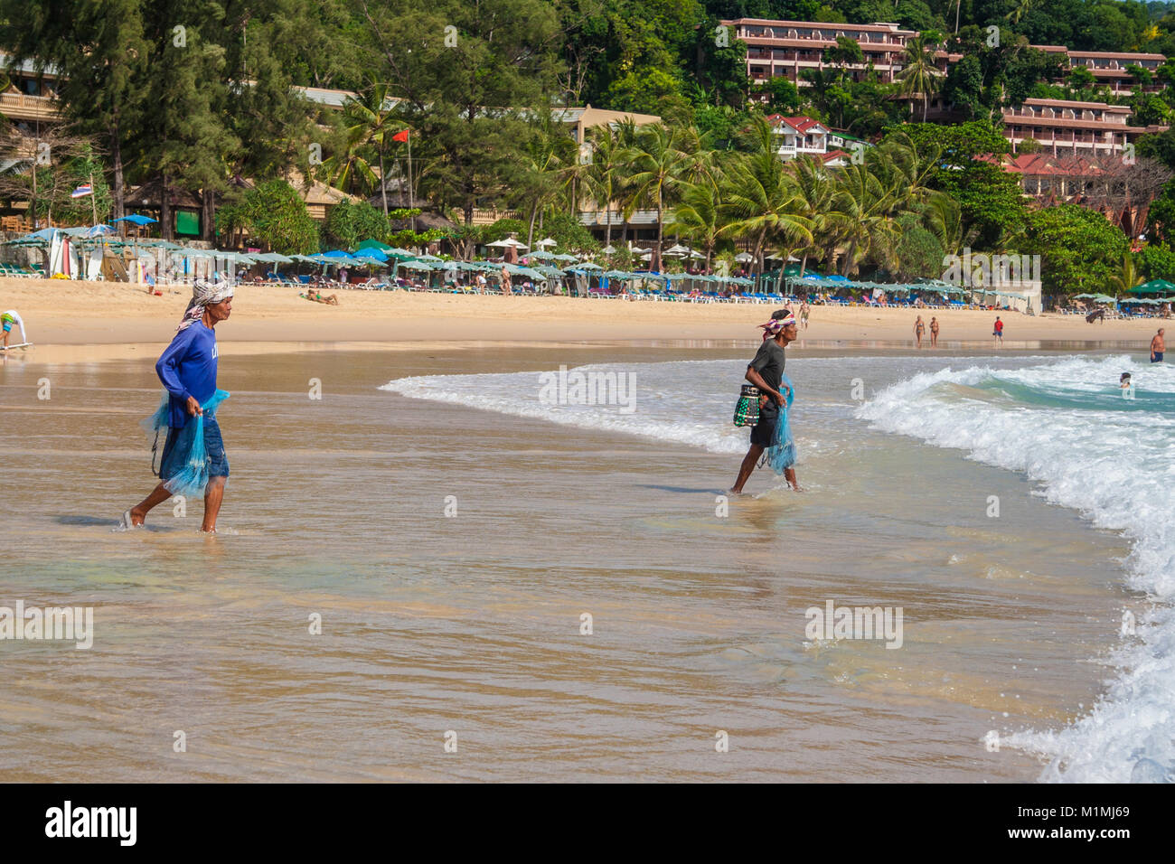 Two local fishermen carrying their net to fish on the Kata Beach, Phuket, Thailand. Taken in June 2009. Stock Photo