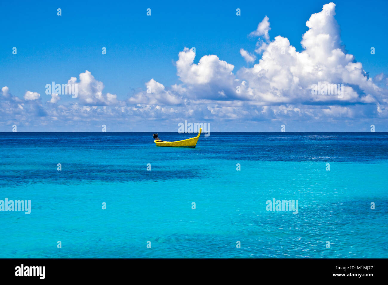 A distinctive yellow long-tail boat floating on the turquoise water at Ter Bay on Racha Island, Phuket, Thailand. Stock Photo
