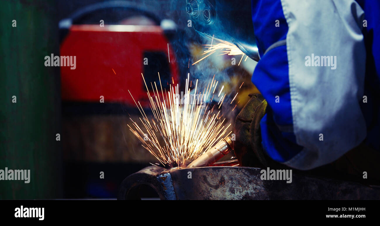 man welds at the factory working in metal industry Stock Photo