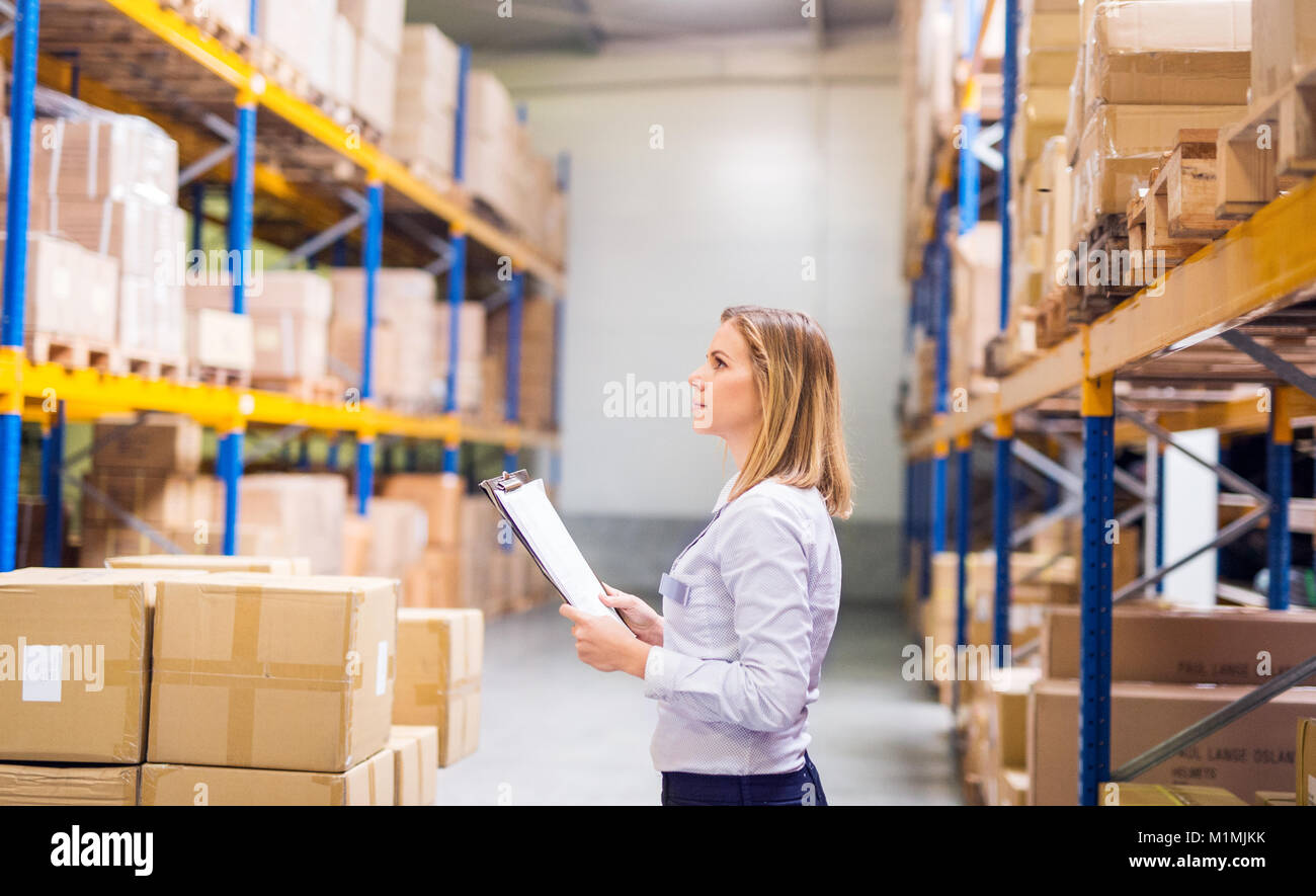 Woman warehouse worker or supervisor with clipboard. Stock Photo