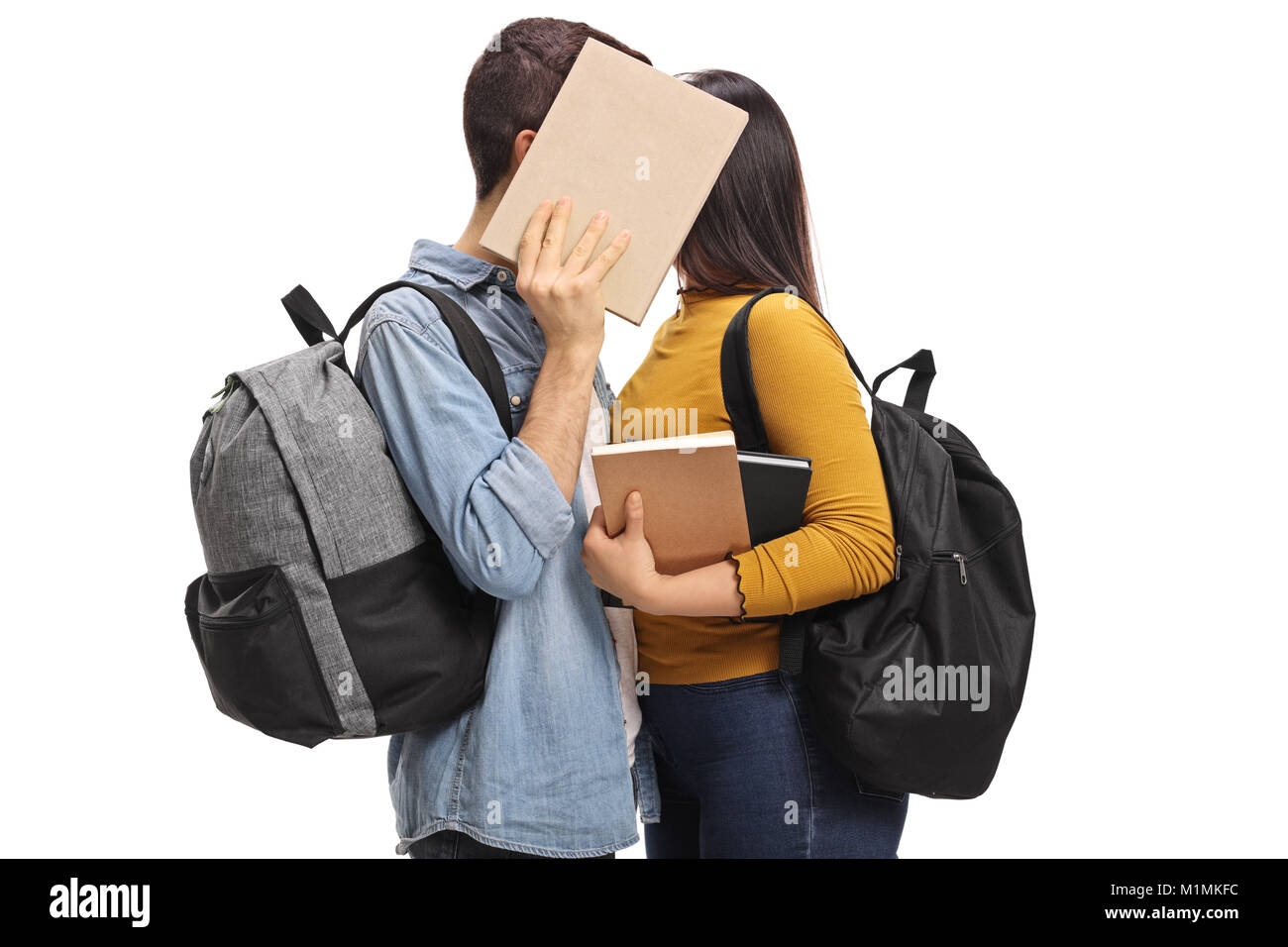 Teen students kissing behind a book isolated on white background Stock Photo