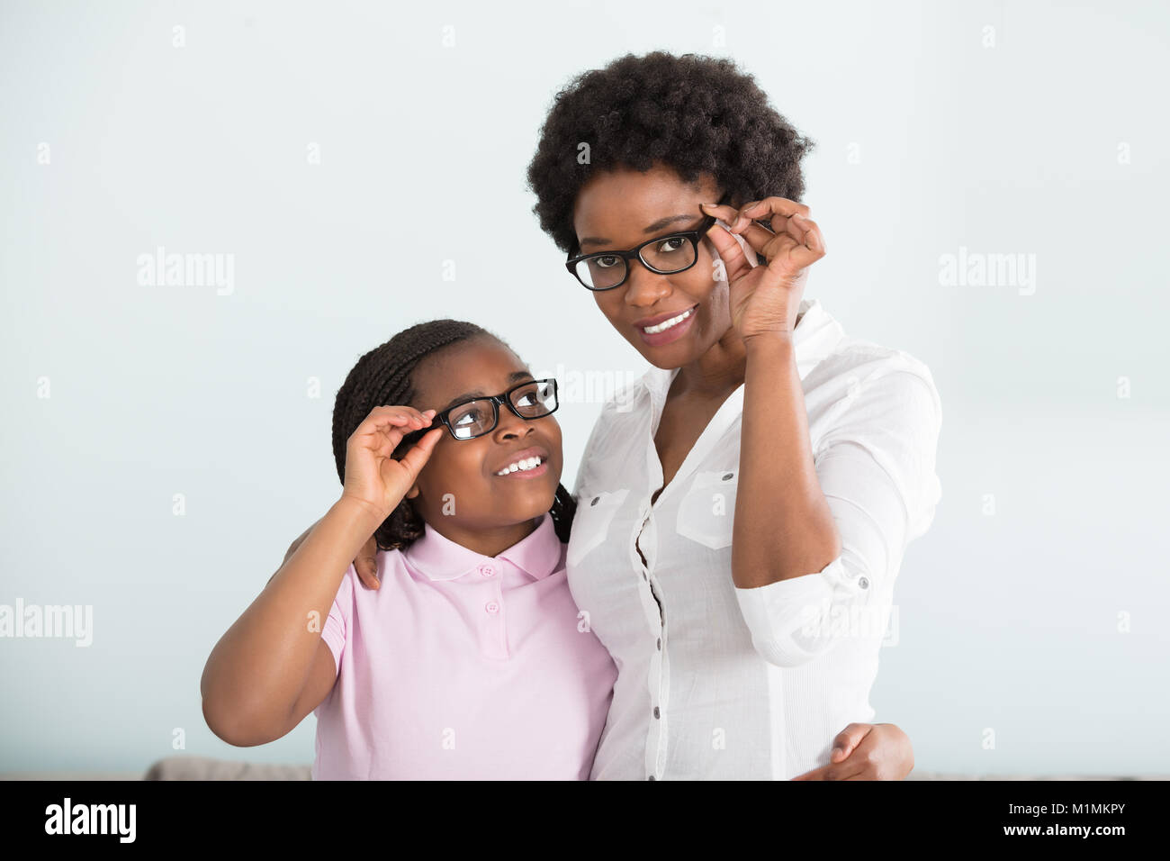 Portrait Of A Smiling Daughter And Mother With Eyeglasses Against White Background Stock Photo