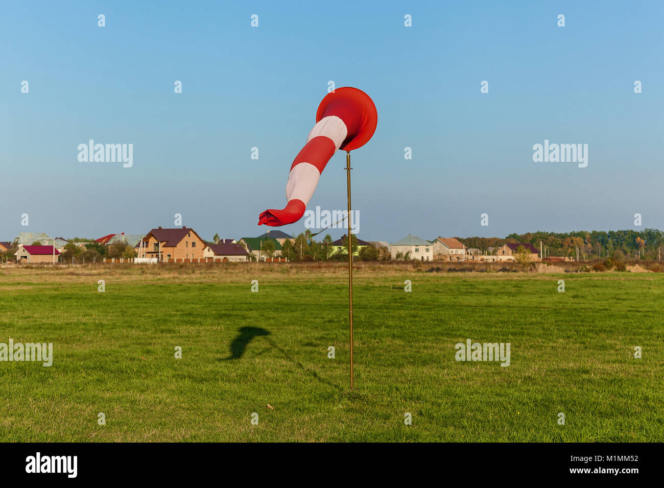 Cone on the runway on the background of grass and houses. Cone on the runway. Stock Photo