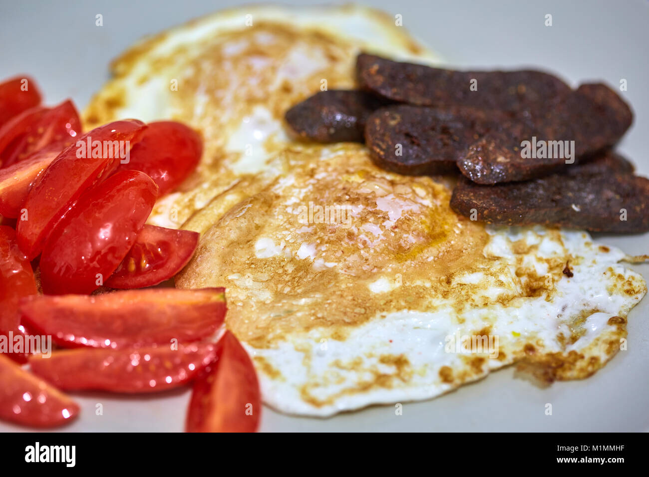 Fried eggs with tomato salad and goden sausages Stock Photo