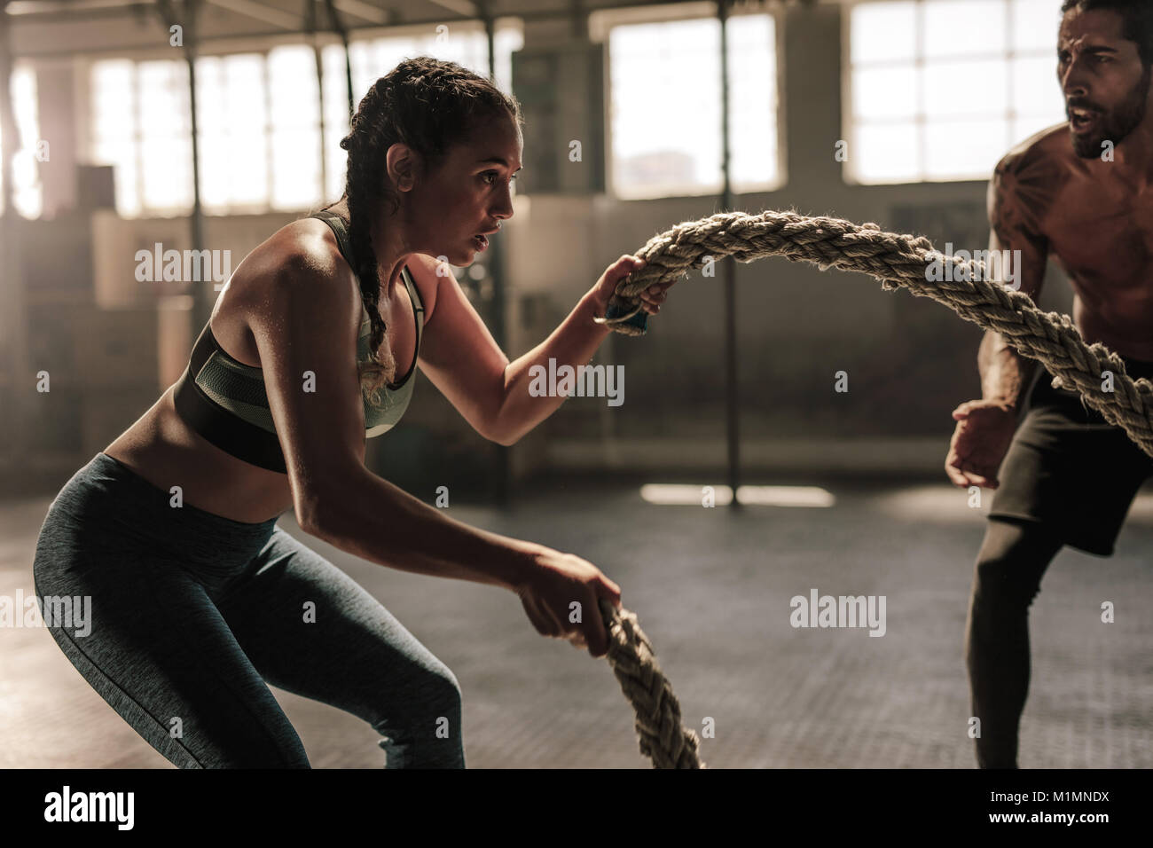 Caucasian strong man pulling rope, cross training gym Stock Photo