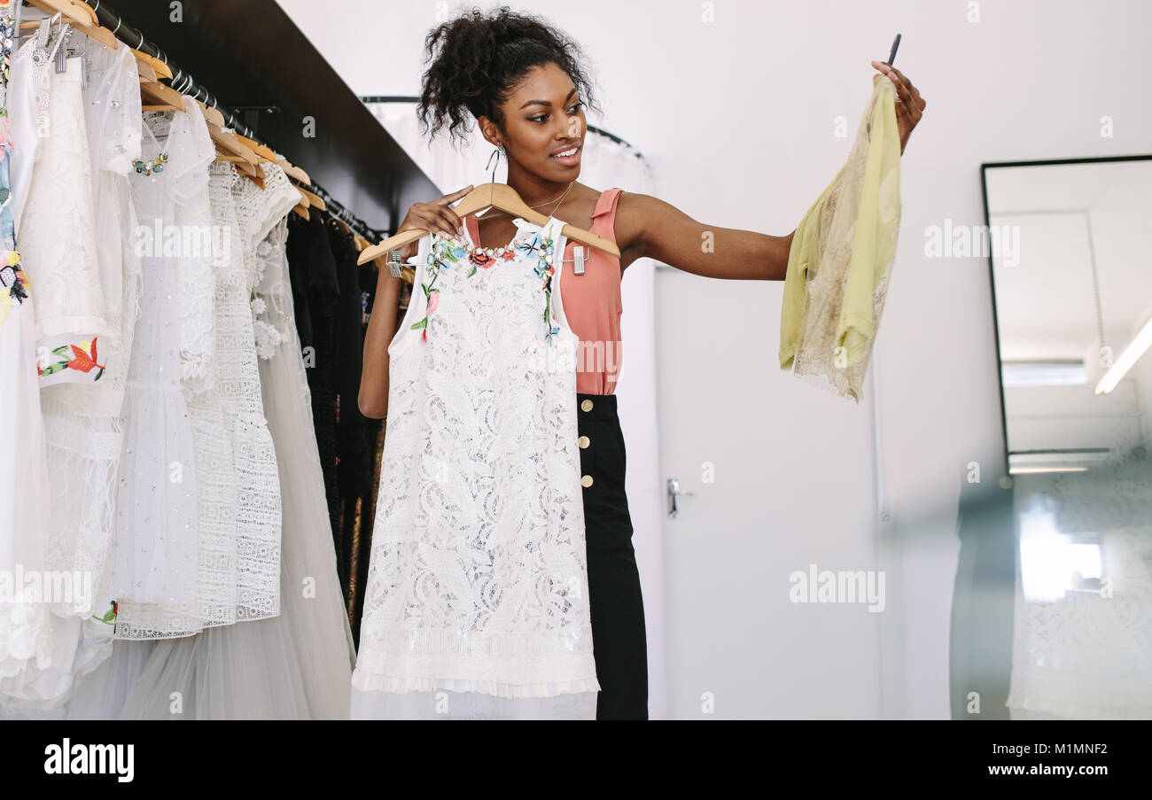Fashion designer having a look at designer dresses in her fashion studio. Customer selecting dresses in a fashion clothes shop. Stock Photo