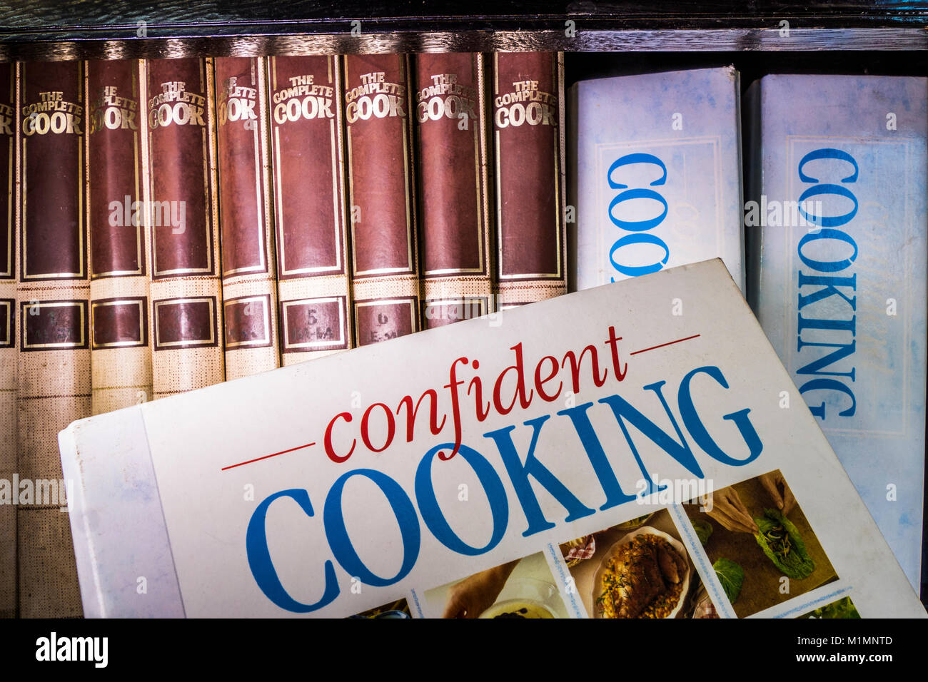 Assortment of self-help, hardback, cookery books with recipes, in a row on a book case, with one entitled ‘Confident Cooking’ at the front. UK. Stock Photo