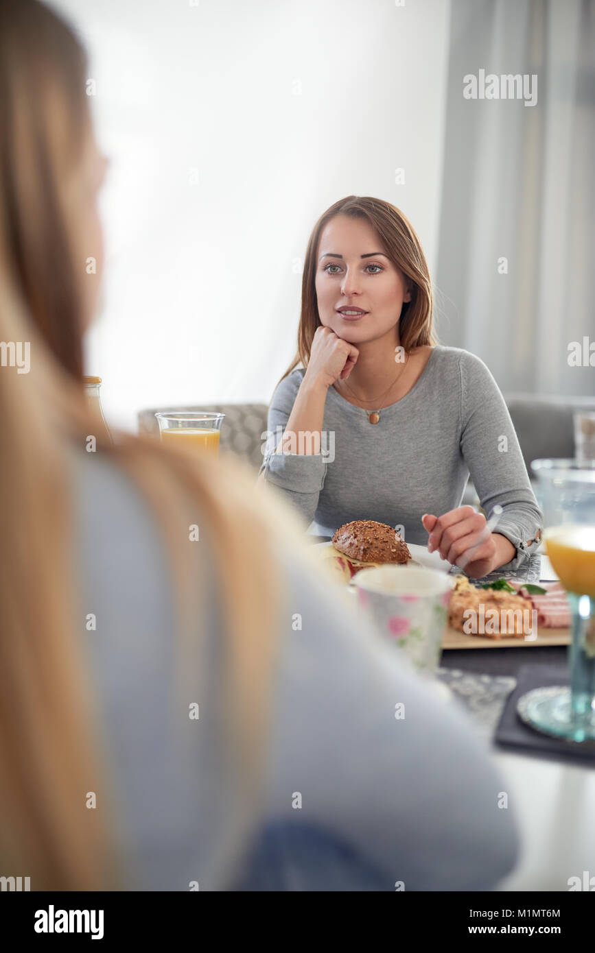 Attractive young teenage girl sitting listening attentively to her mother as they enjoy quality time together over a hearty breakfast in an over the s Stock Photo