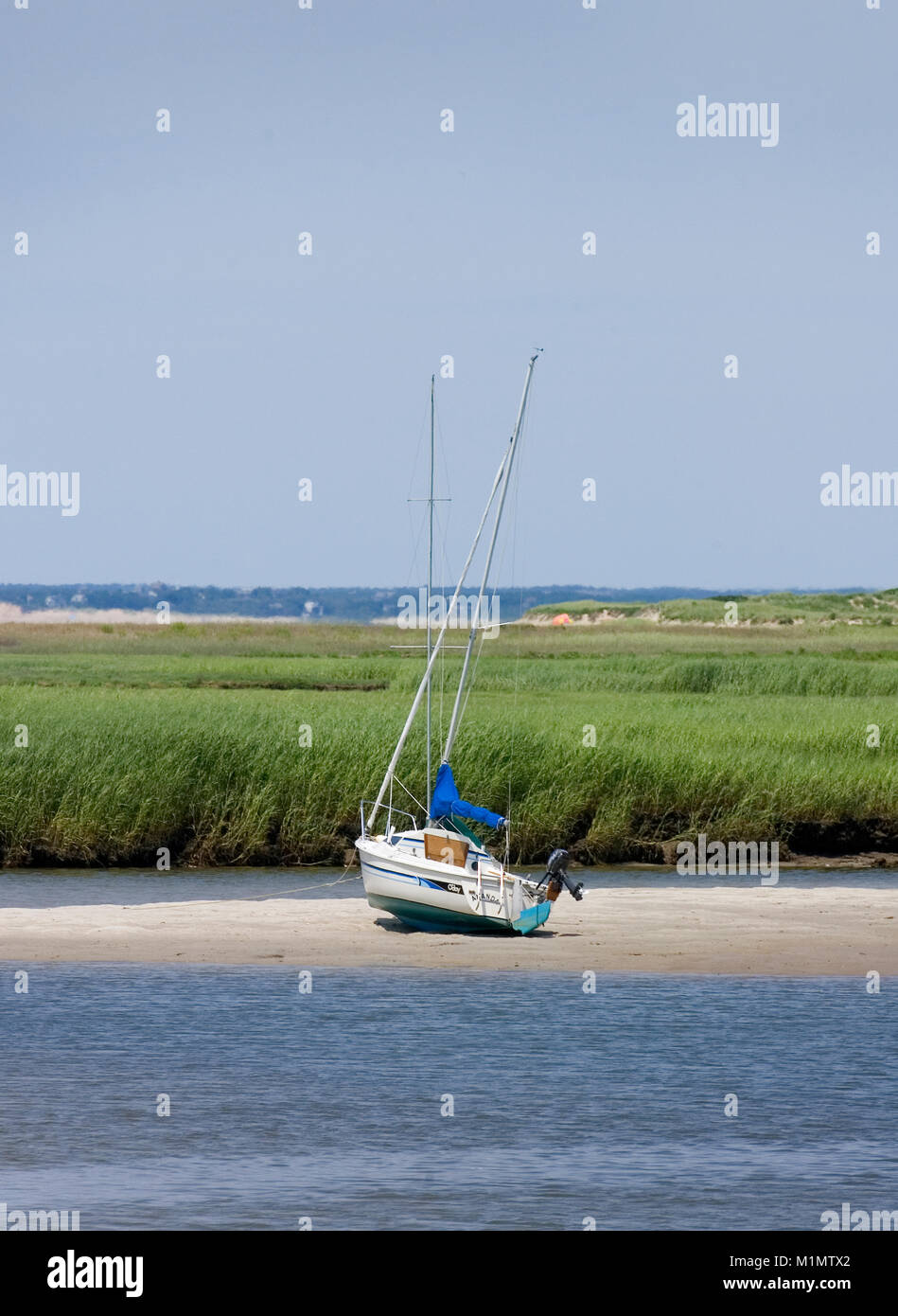 'High and Dry' A sailboat stranded on a sand bar at low tide in Rock Harbor * Orleans, Massachusetts on Cape Cod * Stock Photo