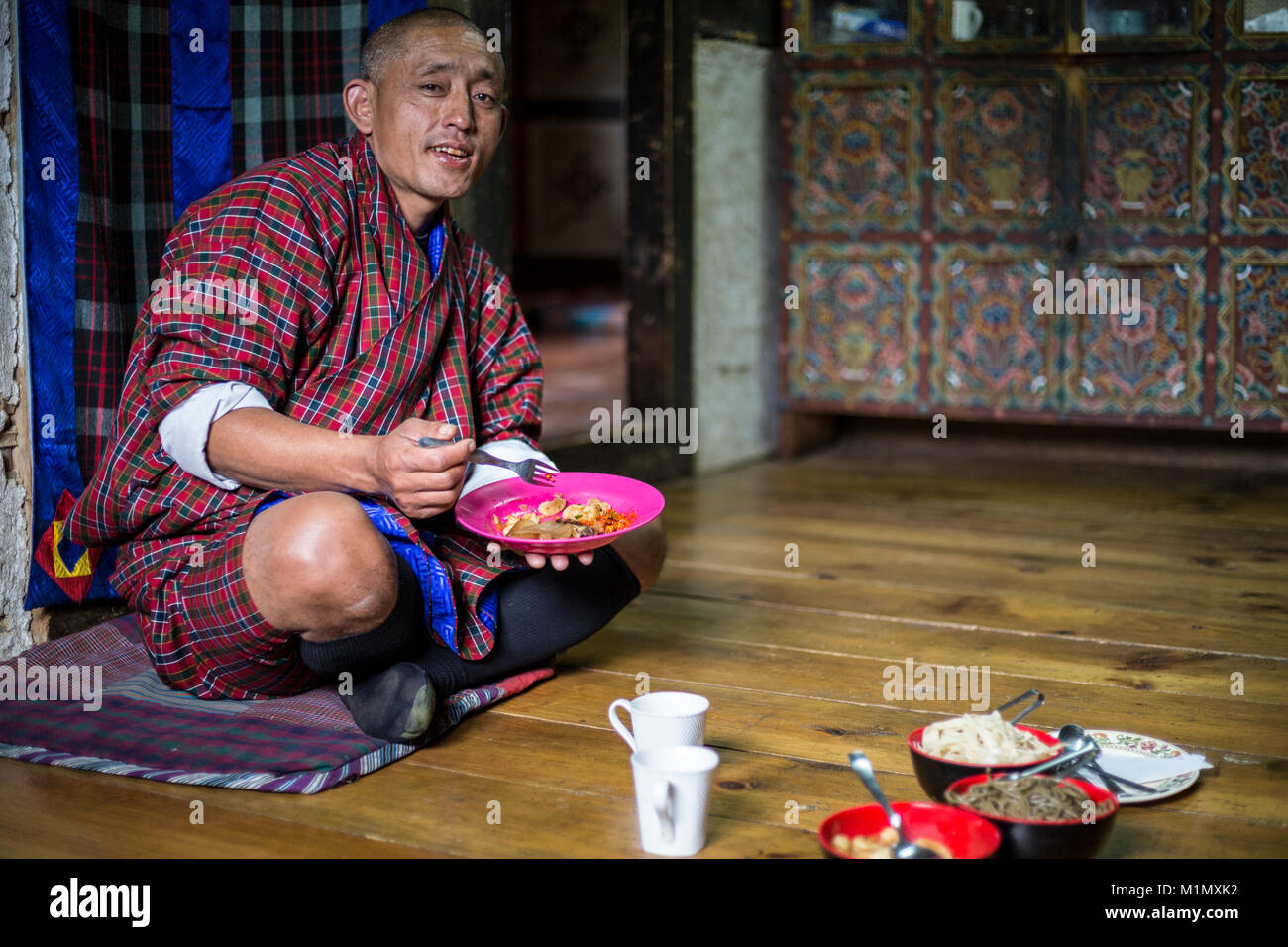 Bumthang, Bhutan.  Bhutanese Wearing Traditional Gho Having his Lunch. Stock Photo