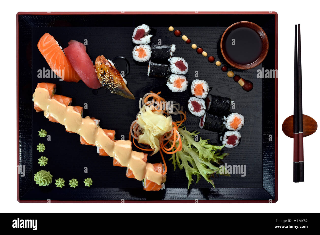 Sushi dish with sauce on UraMaki, Maki, NIGIRI with salmon, tuna, eel, fresh ginger, wasabi, soy sauce, chopsticks, on Japanese wooden plate, Sushi-Ge Stock Photo