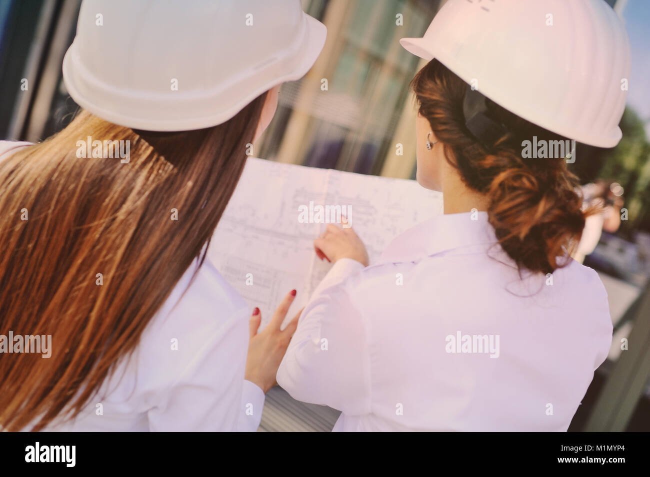 Pretty Engineers Two young pretty business women industrial engineers in construction ...