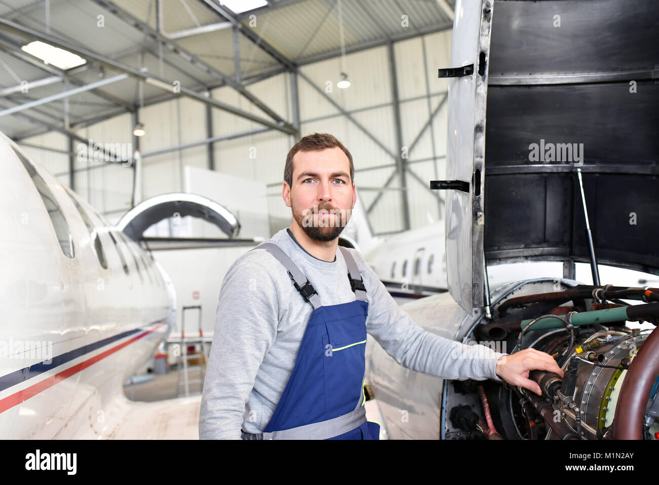 Portrait of an aircraft mechanic in a hangar with jets at the airport - Checking the aircraft for safety and technical function Stock Photo