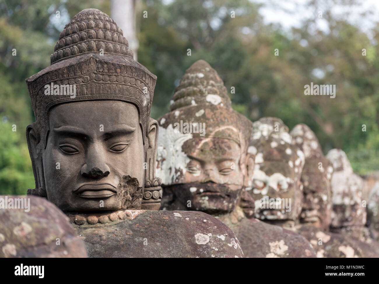 Faces of god statues along the stone bridge in front of the South Gate of Angkor Thom, Cambodia Stock Photo
