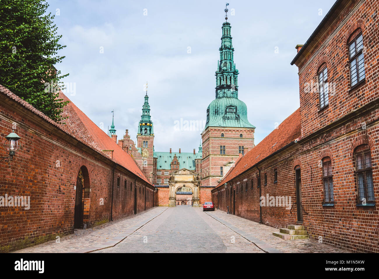 Entrance to Frederiksborg castle in Copenhagen, Denmark - September, 24th, 2015. Red brick fortress wall and green copper spiels of towers of renaissa Stock Photo