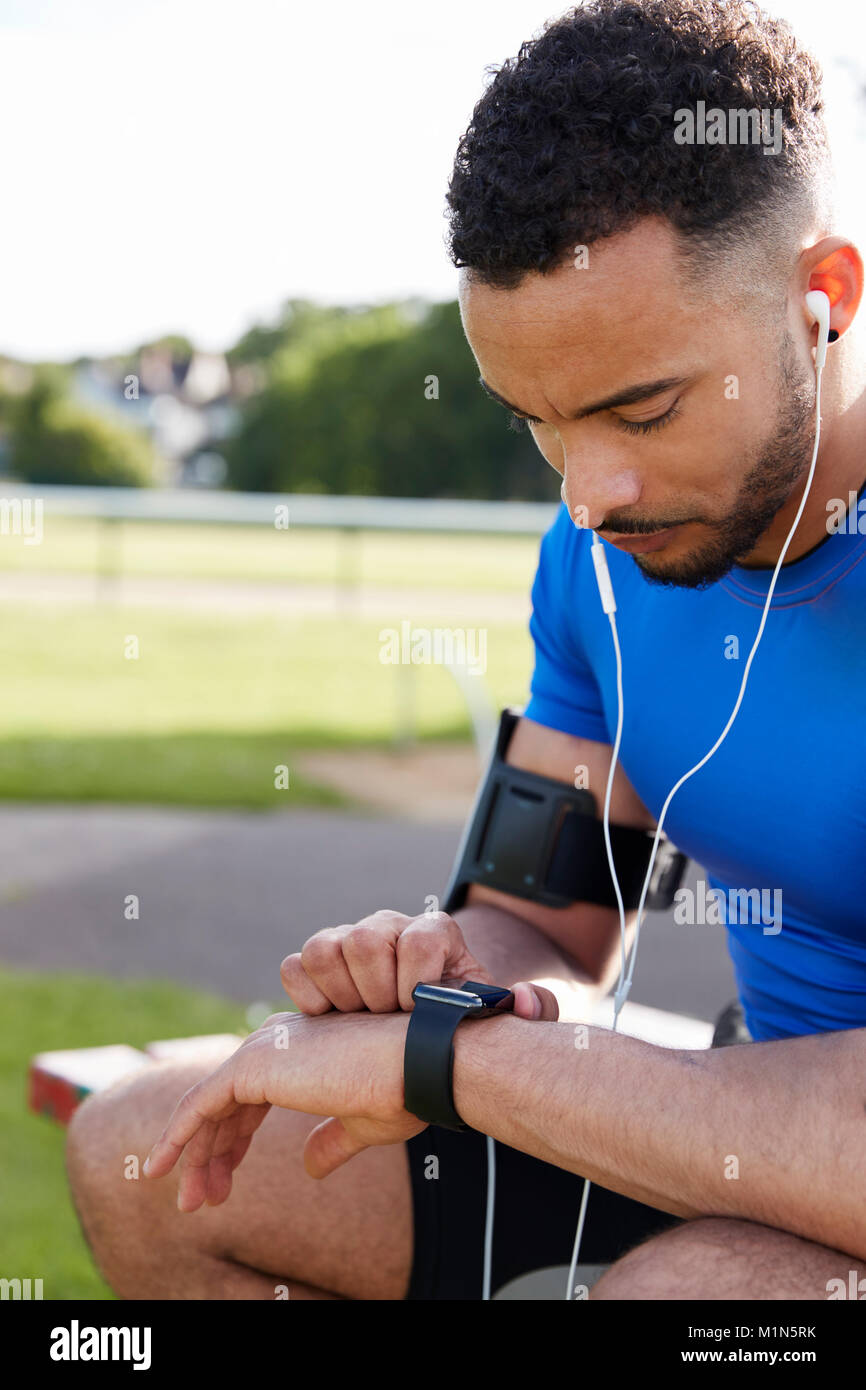 Young male athlete using fitness app on smartwatch, side view Stock Photo