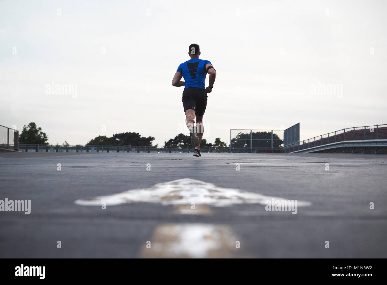 Male athlete running on a road away from camera, full length Stock Photo